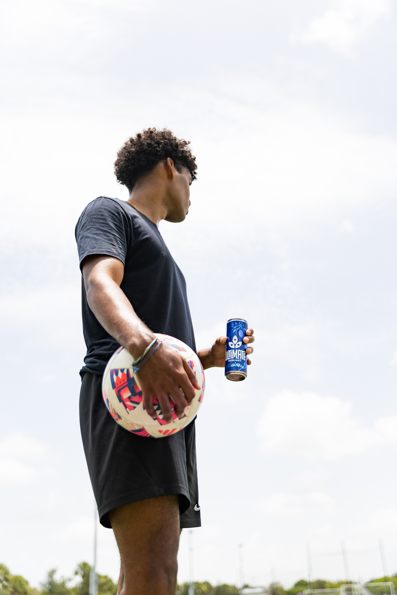 Person holding a soccer ball and an Ultimate can